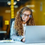 Call center agent with headset working on support hotline in modern office. Video conference.